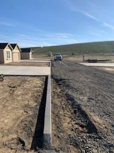 A car is driving down a dirt road next to a concrete curb.