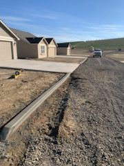 A concrete driveway is being built in front of a row of houses.