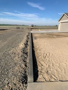 A concrete curb is being built next to a gravel road.