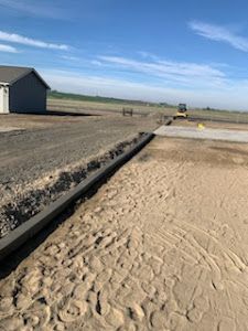 A dirt road going through a field with a house in the background.