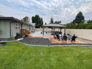 There is a gazebo in the backyard with chairs and a table.