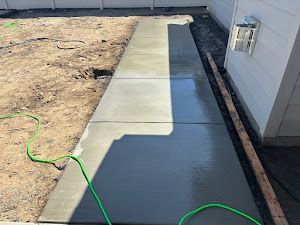 A concrete walkway is being built next to a house.