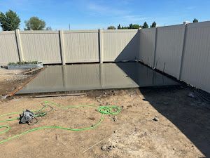 A concrete slab is being built in a backyard next to a fence.