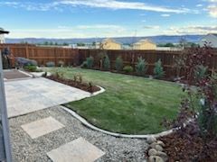 A backyard with a lush green lawn and a wooden fence.