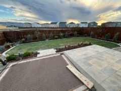 A large backyard with a concrete patio and a fence surrounding it.