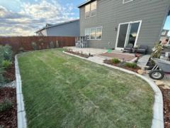 The backyard of a house with a lush green lawn and a patio.