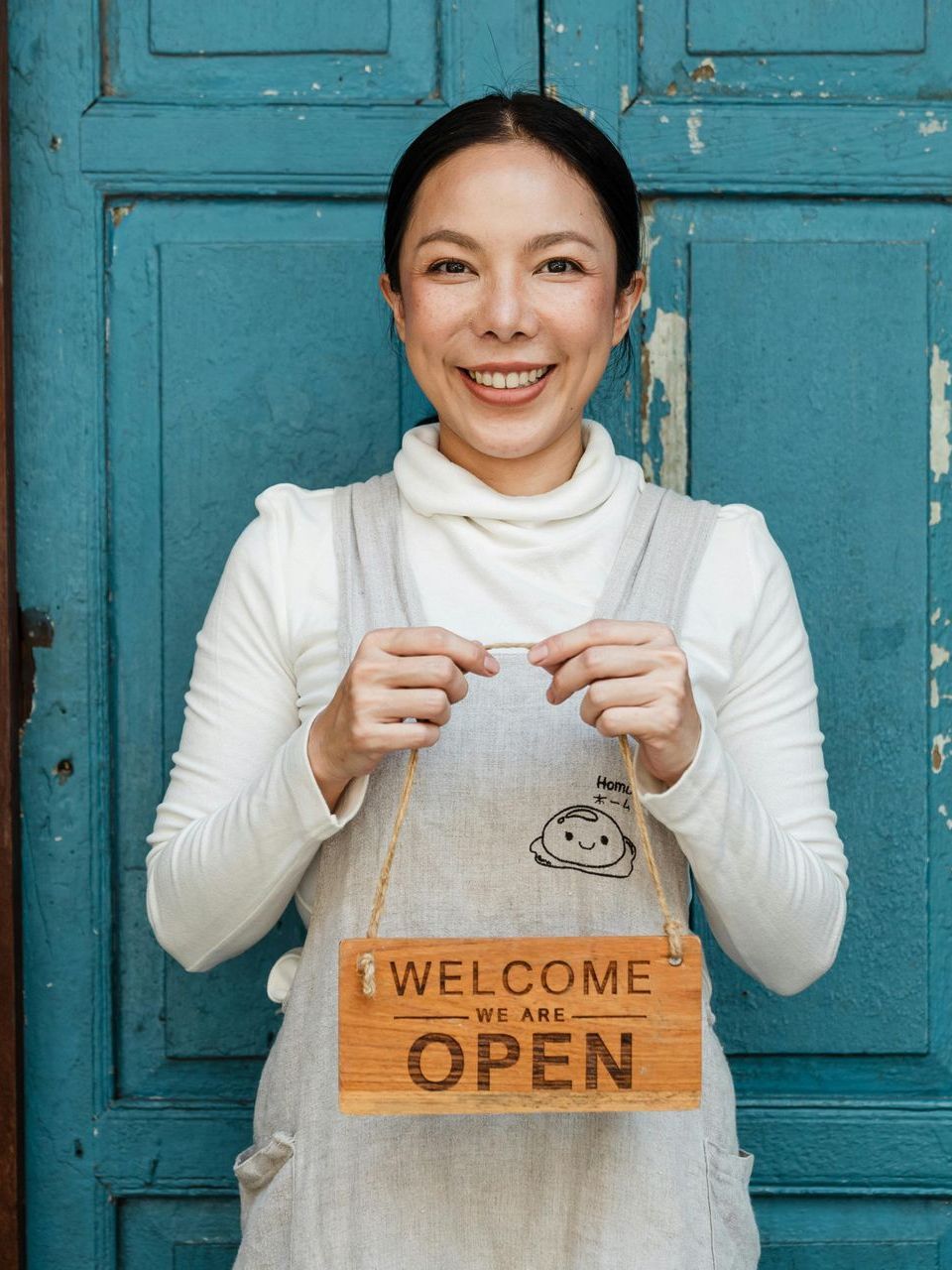 A woman is holding a sign that says welcome we are open