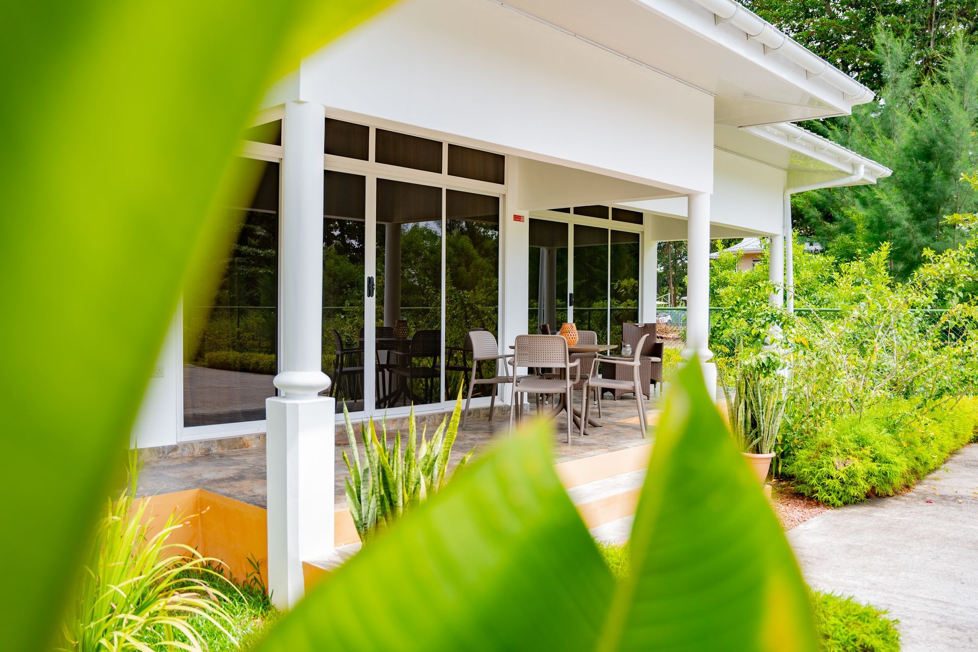 Two black wicker chairs and a small table with flowers on a tiled patio.