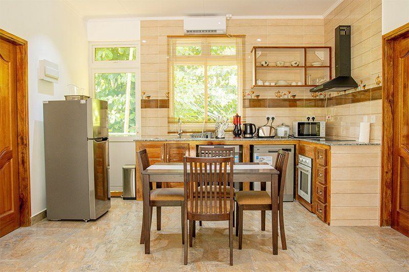 Kitchen with dining table, refrigerator, and appliances. Neutral tones, natural light, and wooden cabinetry.