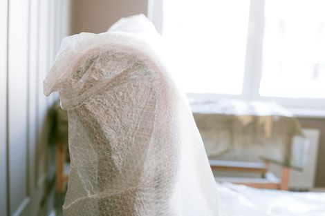 A chair is wrapped in plastic bubble wrap in a room.