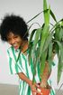 A woman in a green and white striped shirt is holding a potted plant.
