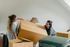 A man and a woman are holding a large cardboard box in a living room.