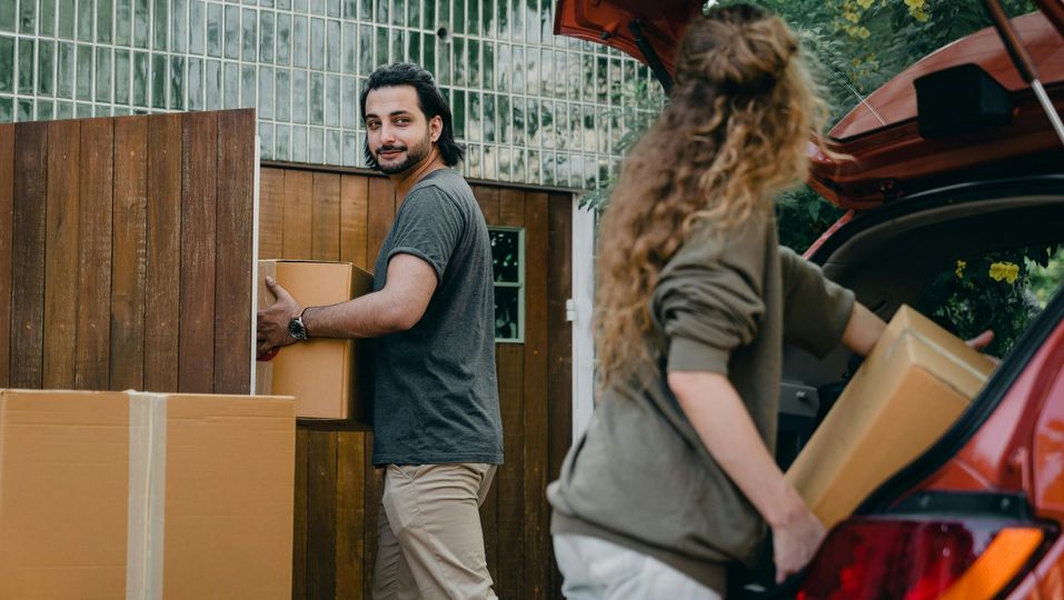 A man and a woman are loading boxes into the back of a car.