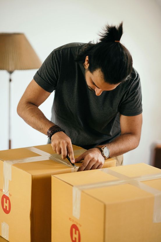 A man is wrapping a cardboard box with tape.