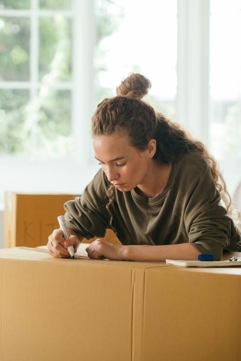 A woman is sitting at a table writing on a piece of paper.