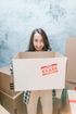 A woman is holding a cardboard box with a glass sticker on it.