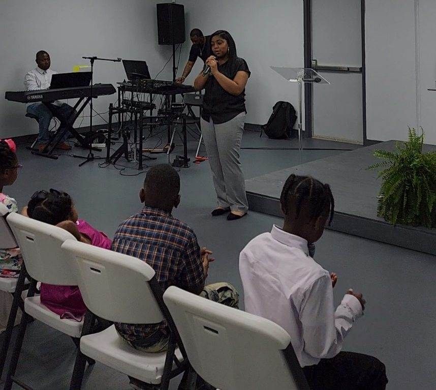Woman speaking to children in a room with musical instruments.