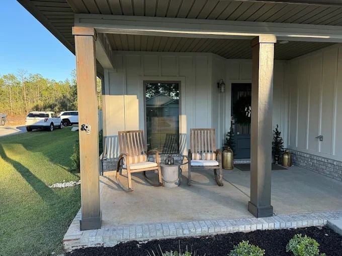 Front porch with two rocking chairs, neutral colors, and a door.