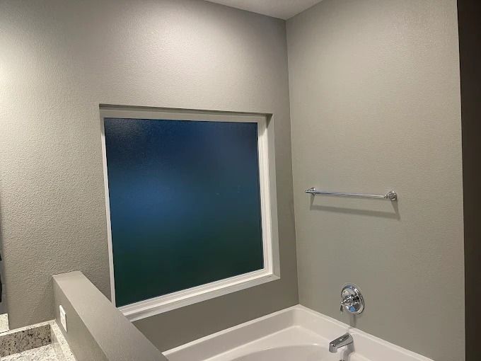 Bathroom with window, tub, towel rack, and light gray walls.