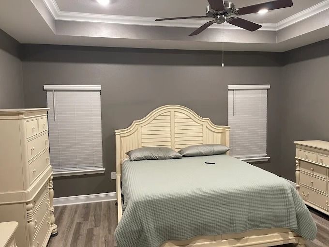 Bedroom with a bed, dressers, gray walls, and white ceiling.
