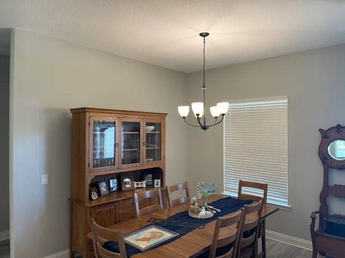 Dining room with wooden furniture, including a hutch, table, chairs, and a chandelier.