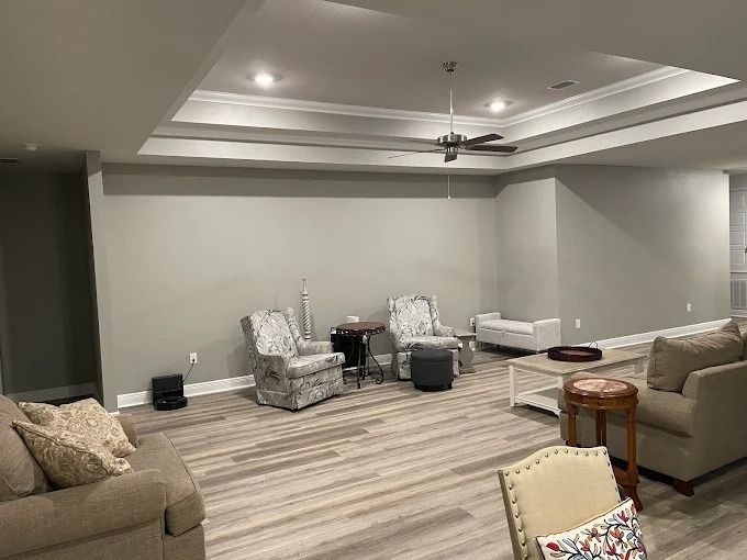 Spacious living room with two patterned armchairs, a sofa, and a coffee table on a light wood floor, neutral walls.