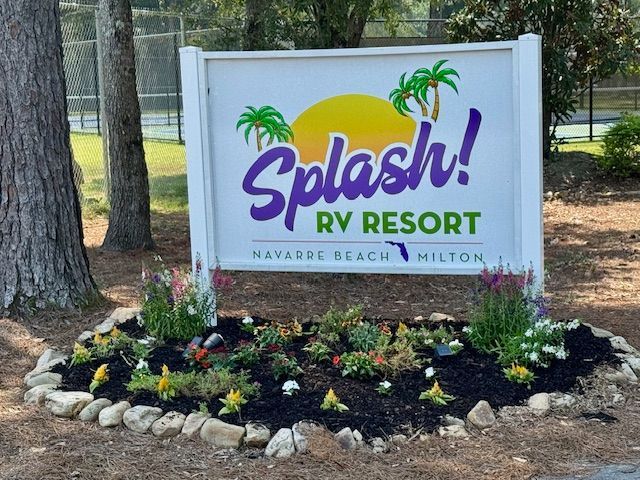 Sign for Splash! RV Resort in Navarre Beach, Florida, with colorful logo, palm trees, and flowers.
