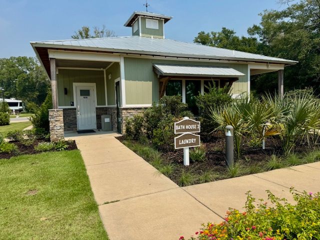 Green bathhouse with laundry sign; pathway, landscaping.