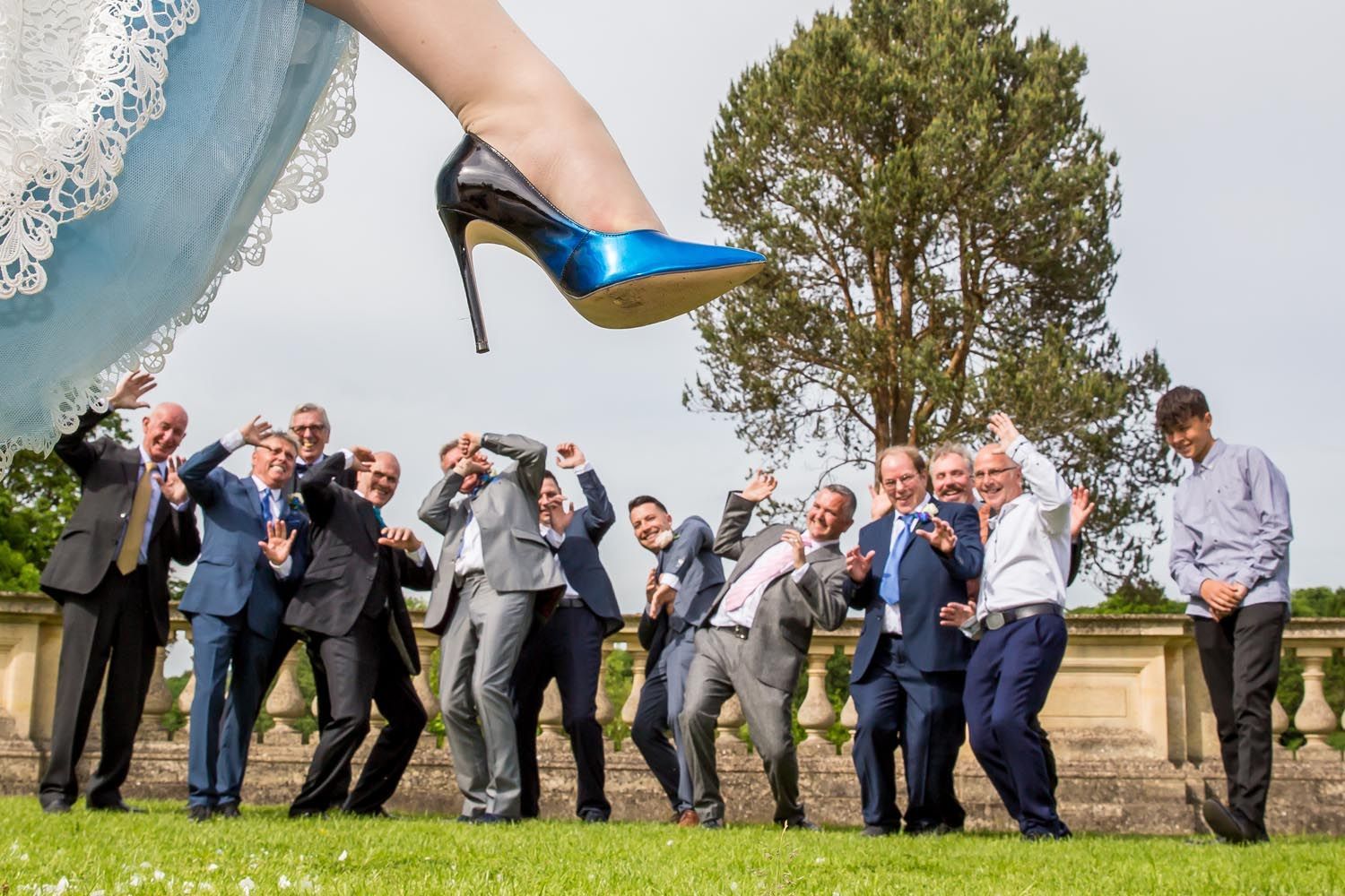 A group of people are posing for a picture with a bride 's foot in the air.