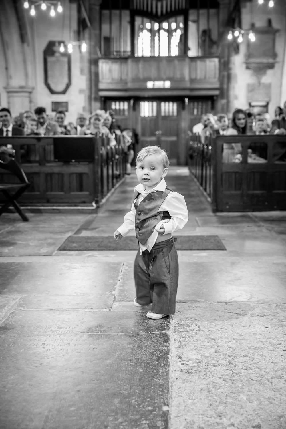 A little boy is walking down the aisle of a church.