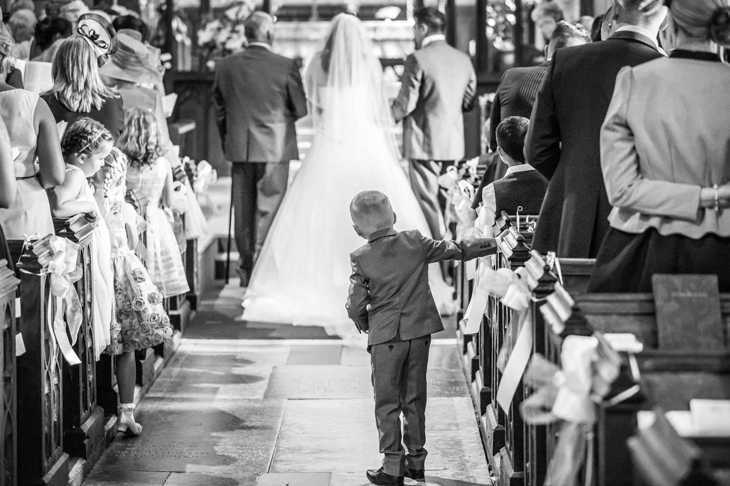 A black and white photo of a bride and groom walking down the aisle of a church.