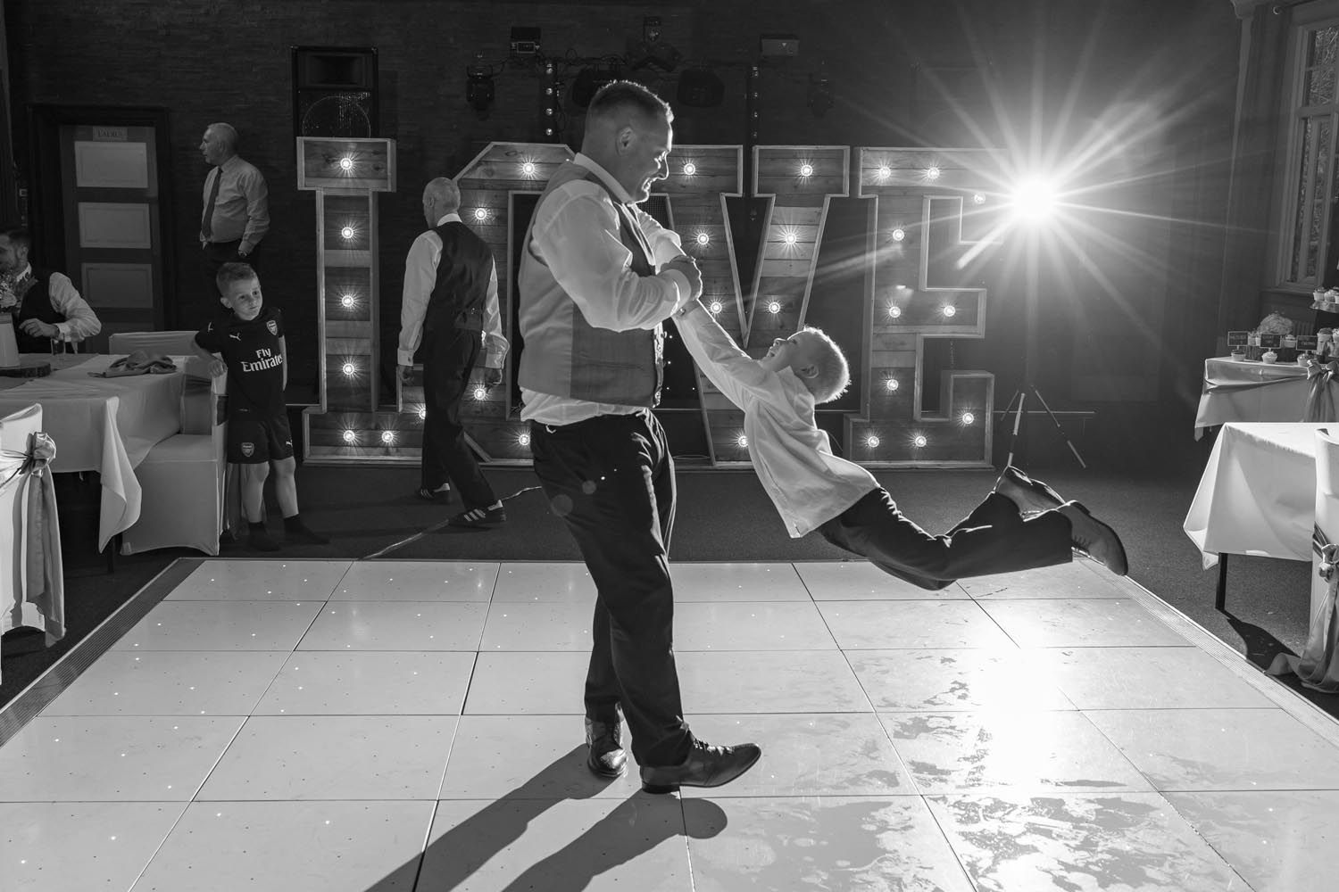A man is holding a child in his arms while dancing on a dance floor.