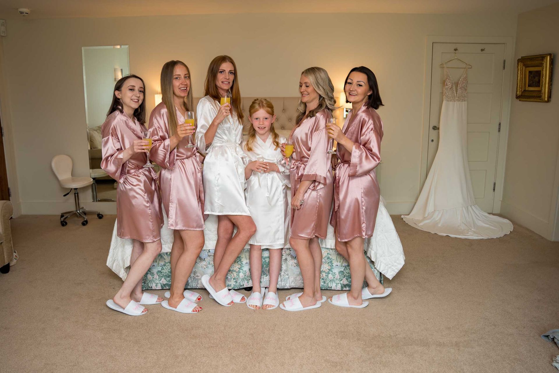 A bride and her bridesmaids are posing for a picture in a bedroom.