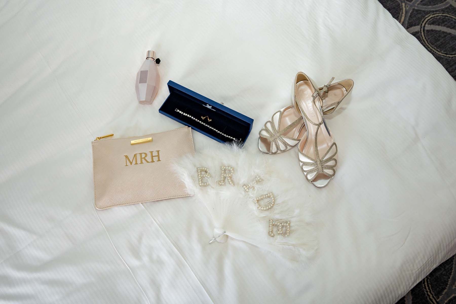 A pair of shoes and a purse are laying on a bed.