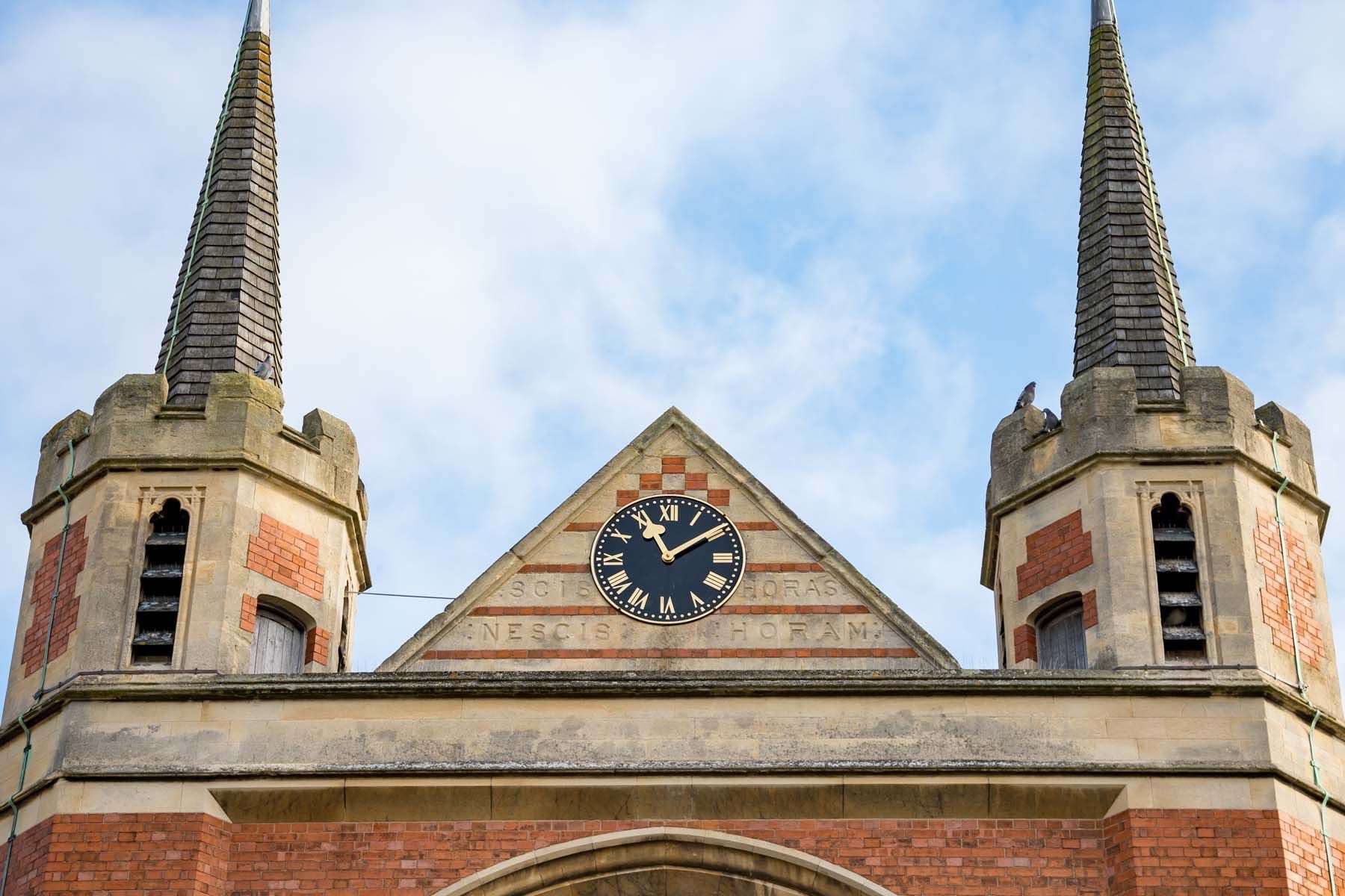 A brick building with two towers and a clock on top of it.