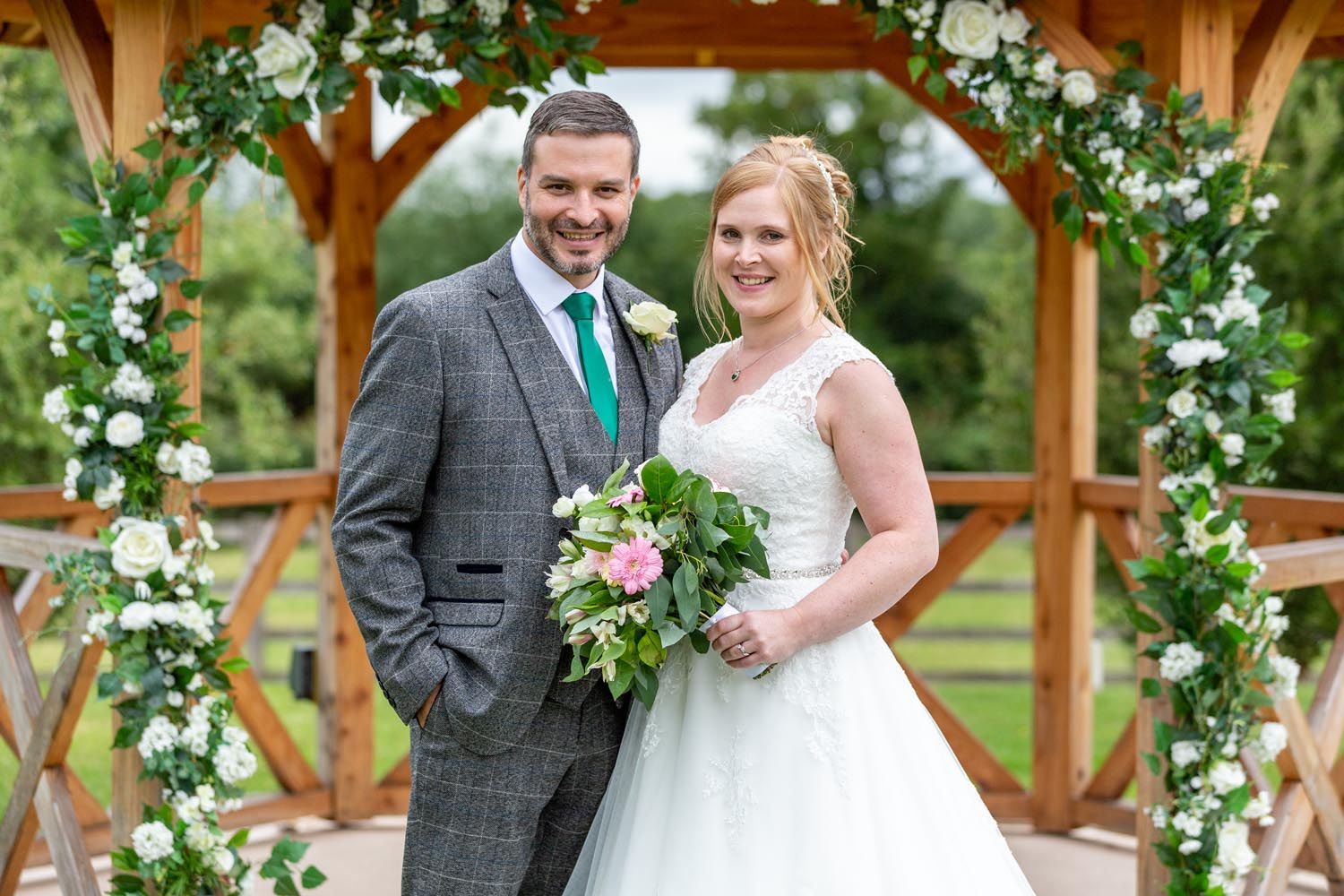 A bride and groom are posing for a picture in front of a gazebo.