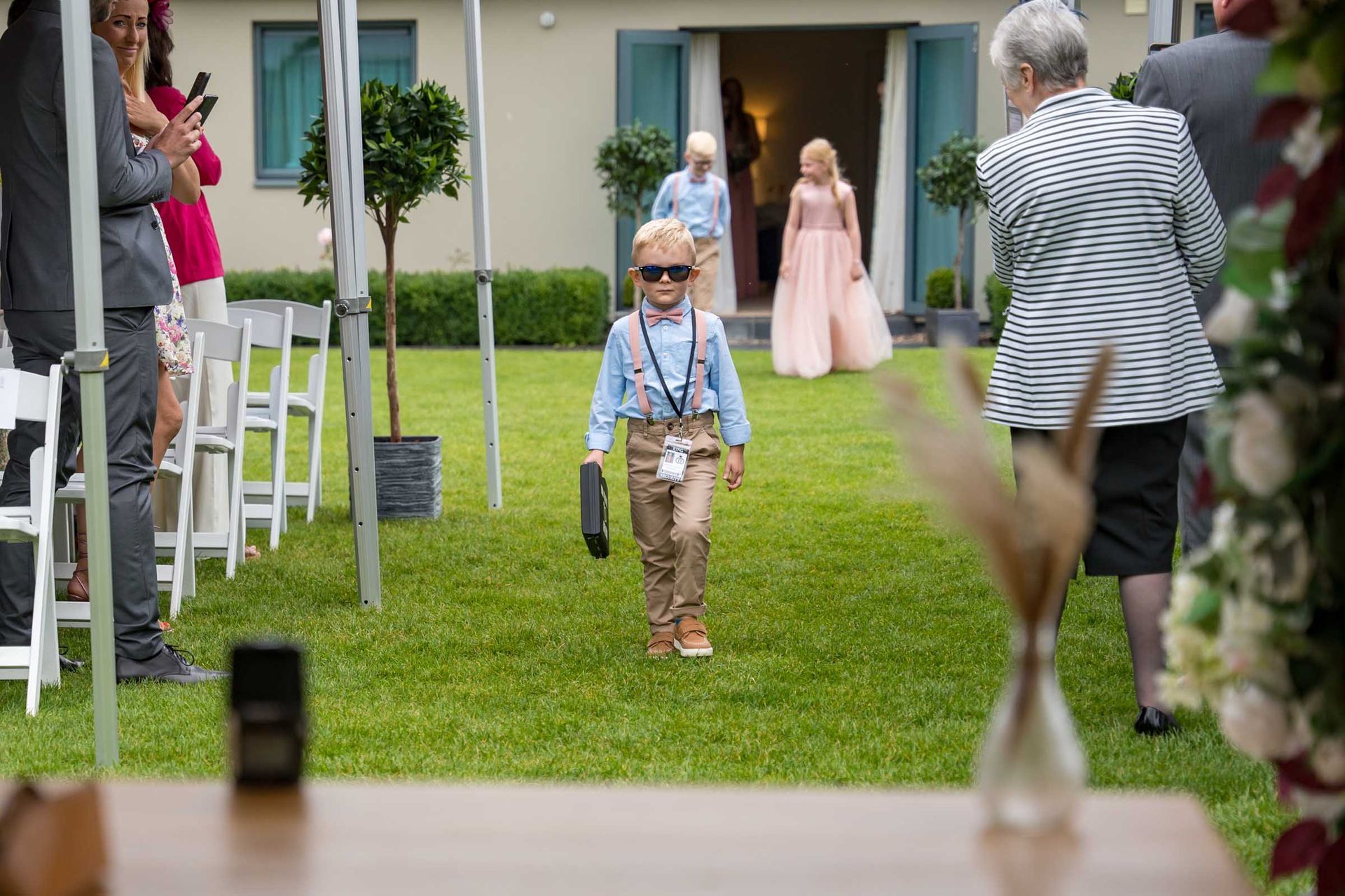 A little boy is walking down the aisle at a wedding.