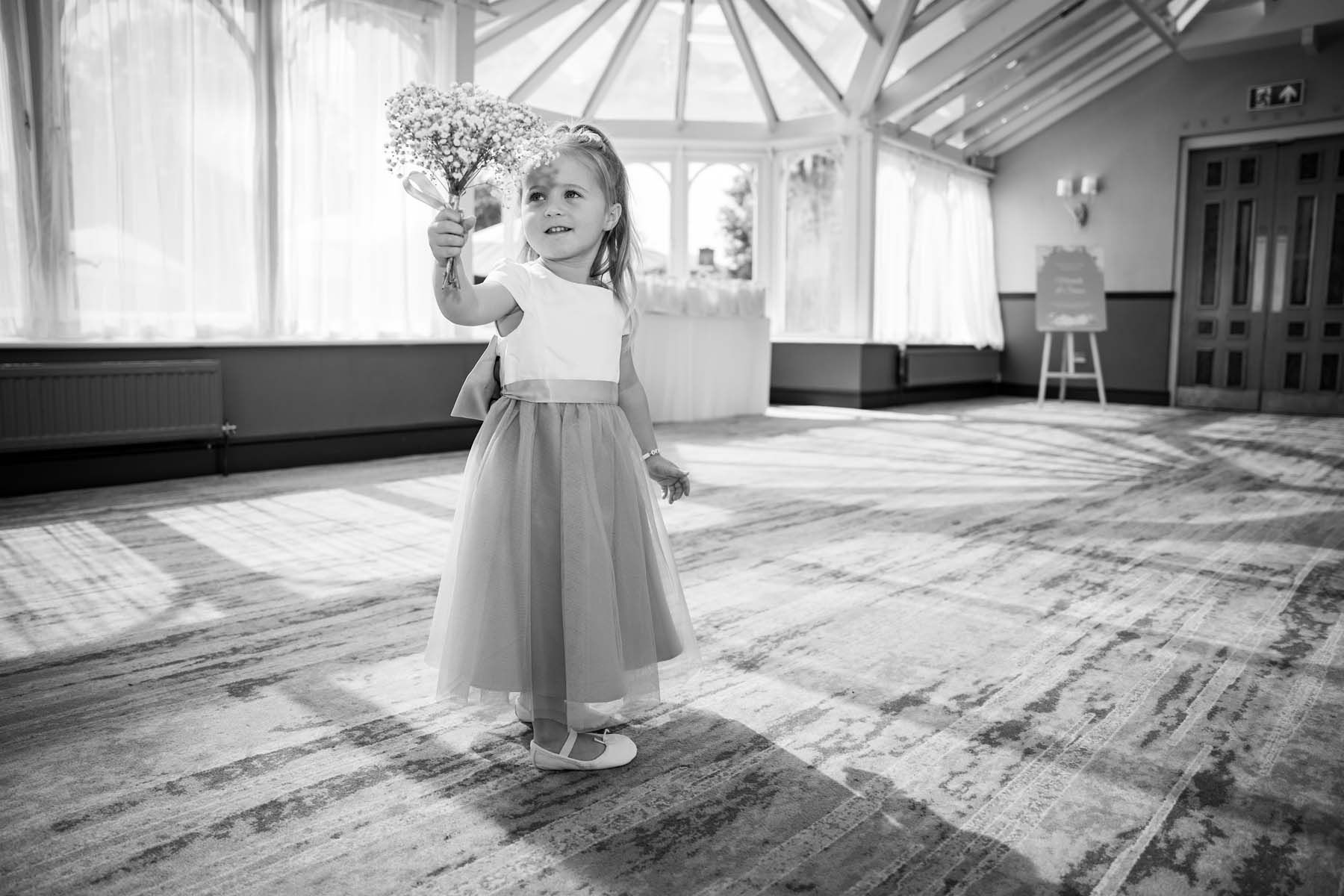 A flower girl is holding a bouquet of flowers in a black and white photo.