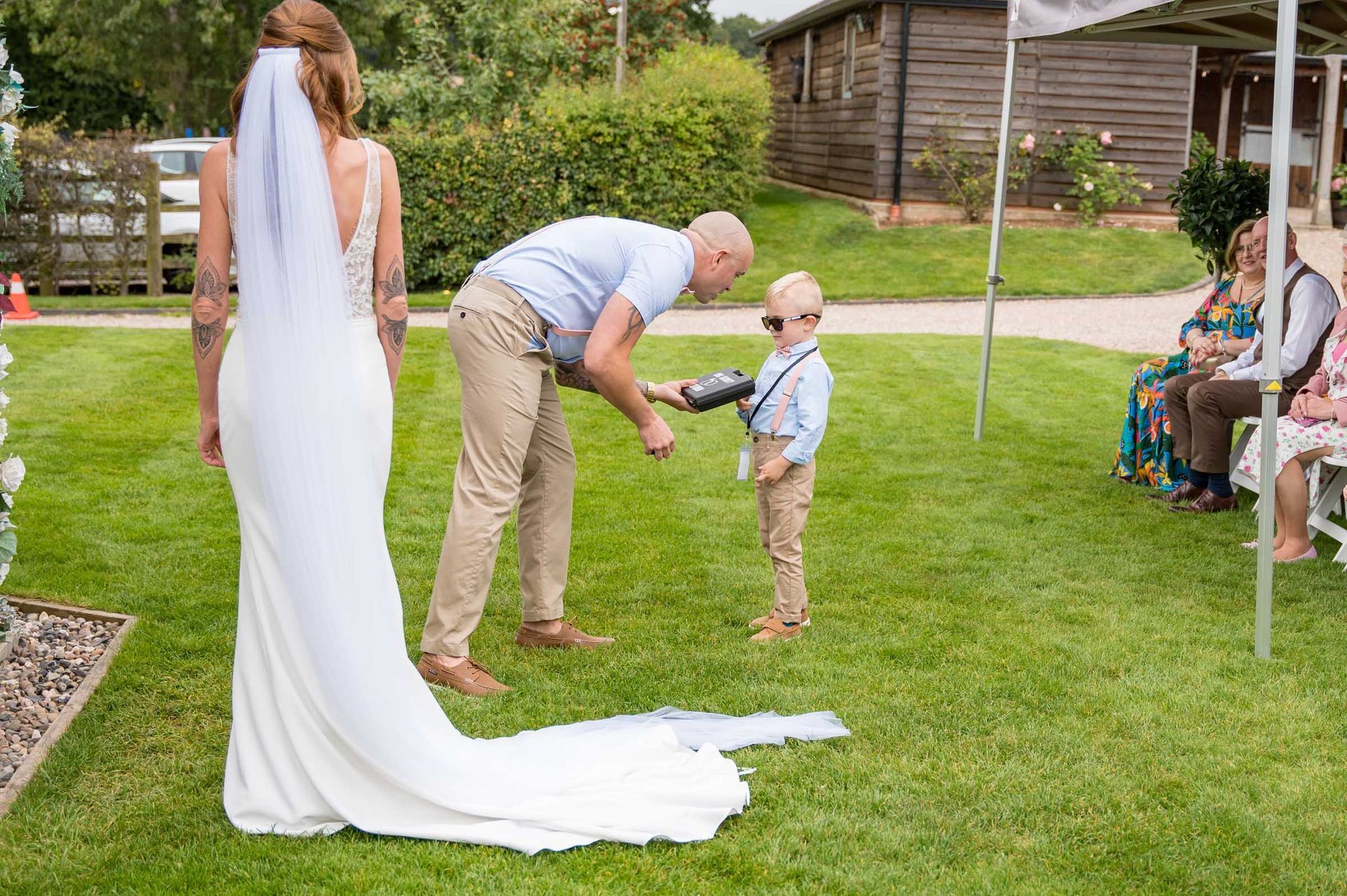 A bride and groom are standing in the grass with a little boy.