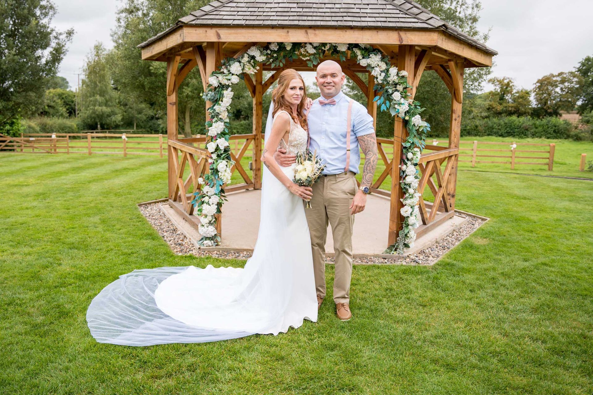 A bride and groom are posing for a picture in front of a gazebo.