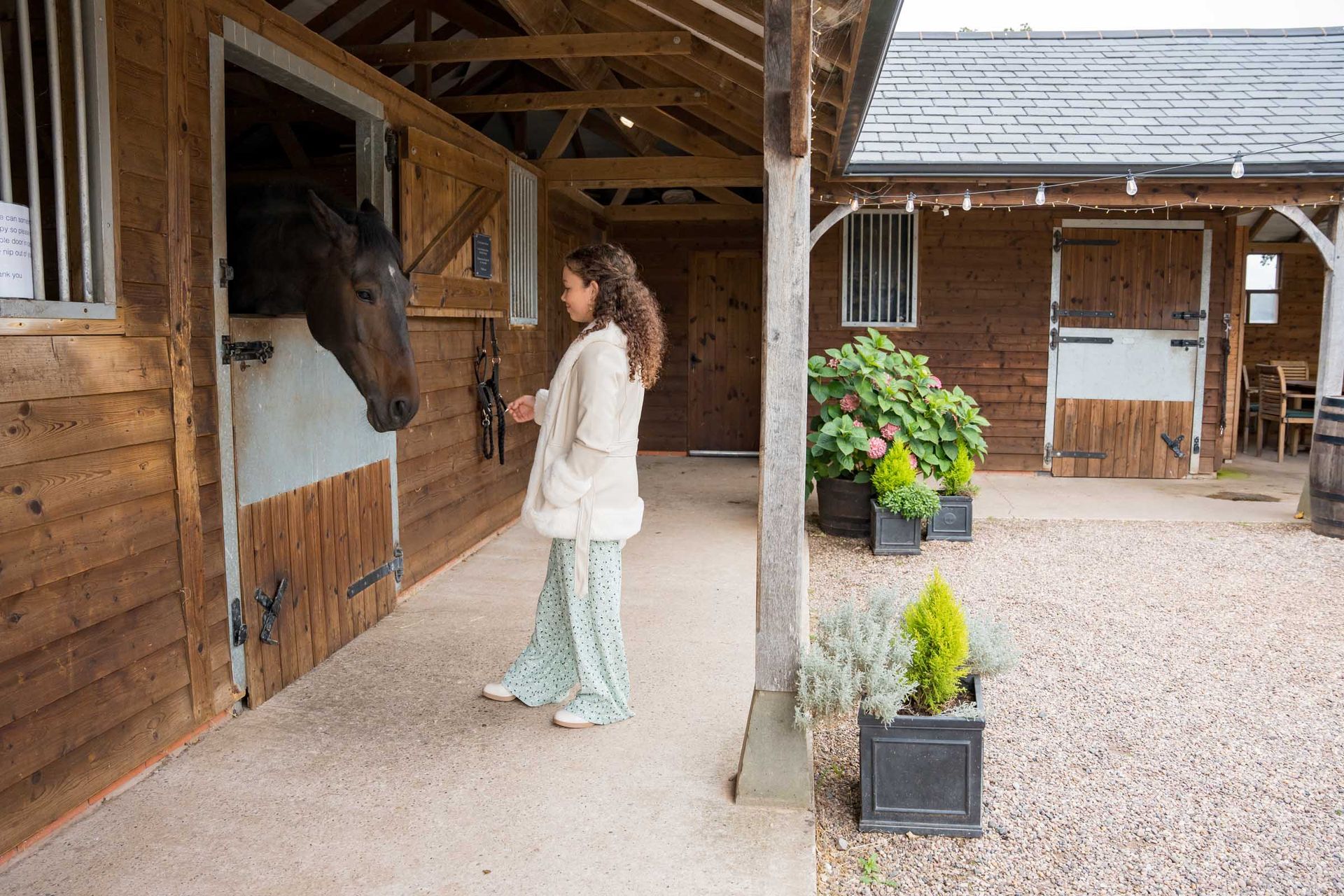 A woman is standing next to a horse in a stable.