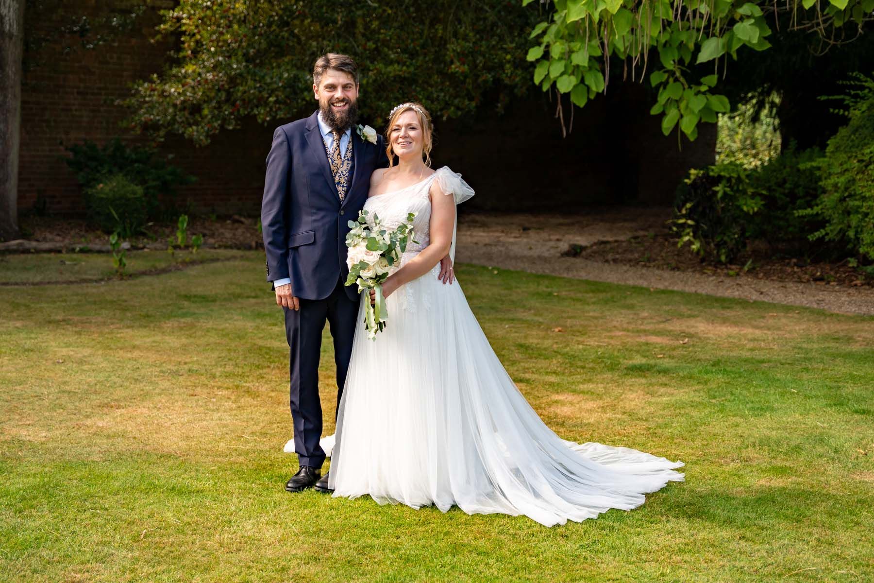 A bride and groom are posing for a picture in the grass.
