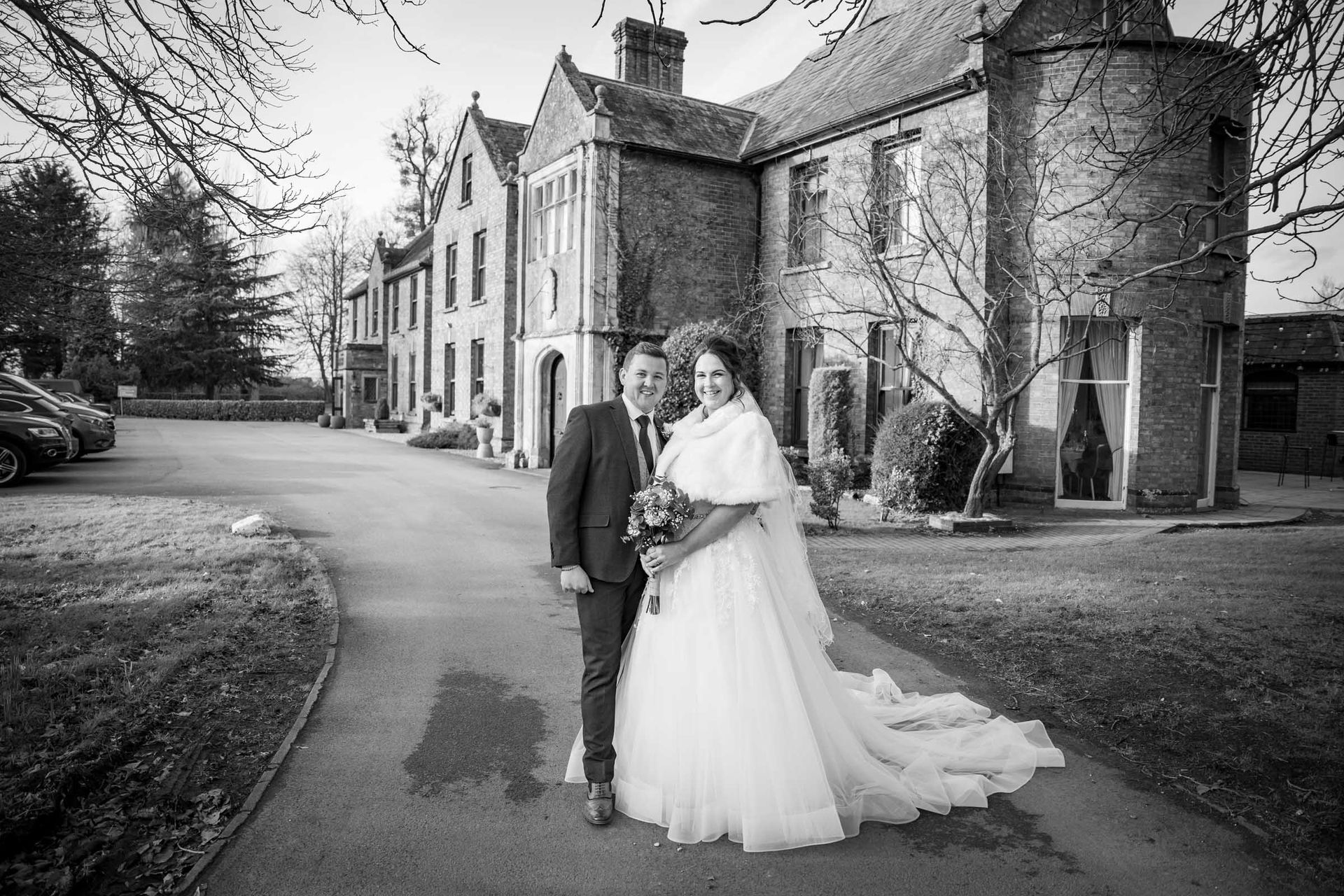 A bride and groom are posing for a picture in front of a large building.