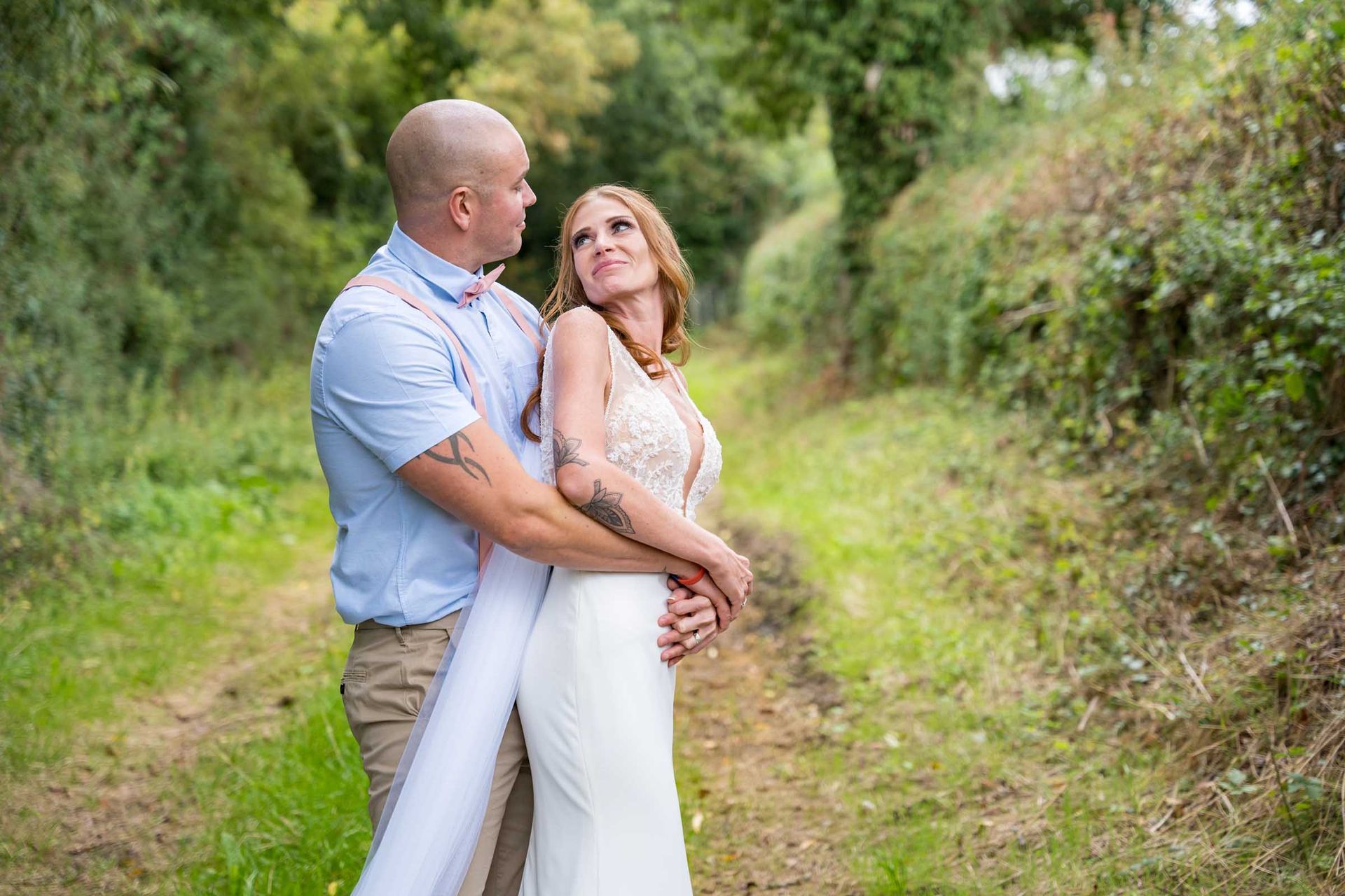 A bride and groom are standing next to each other in a field.