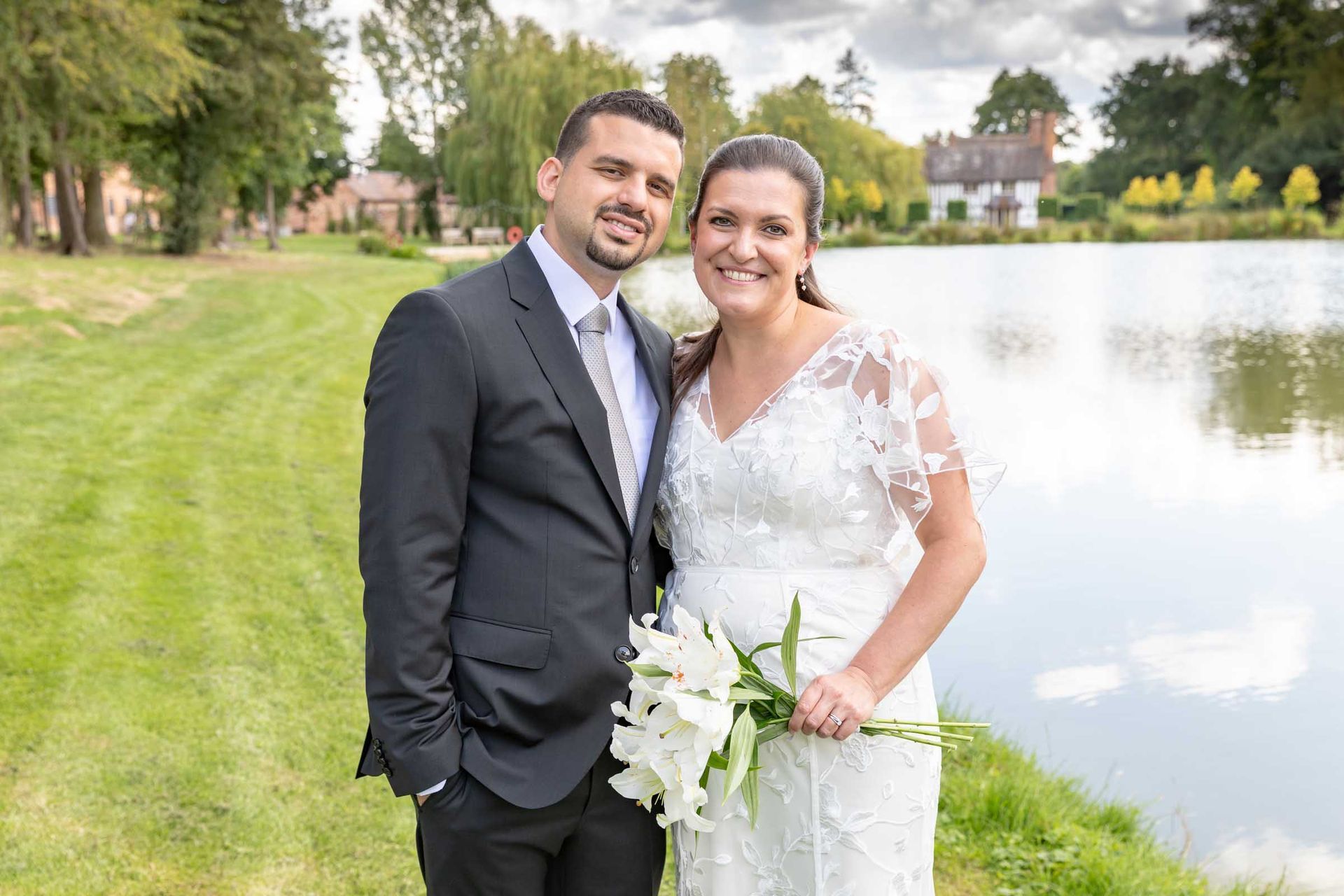 A bride and groom are posing for a picture in front of a lake.