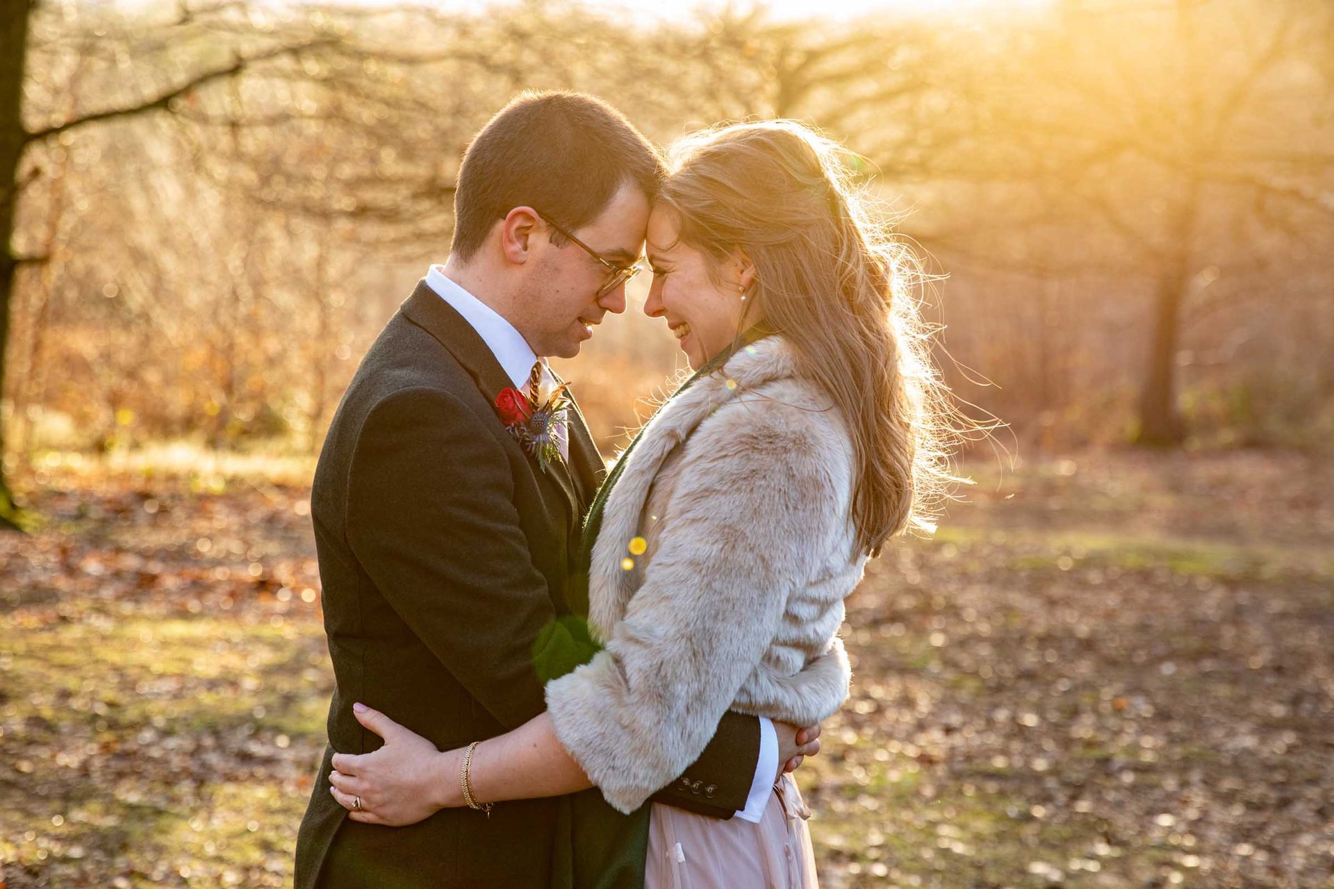 A bride and groom are hugging each other in the woods.