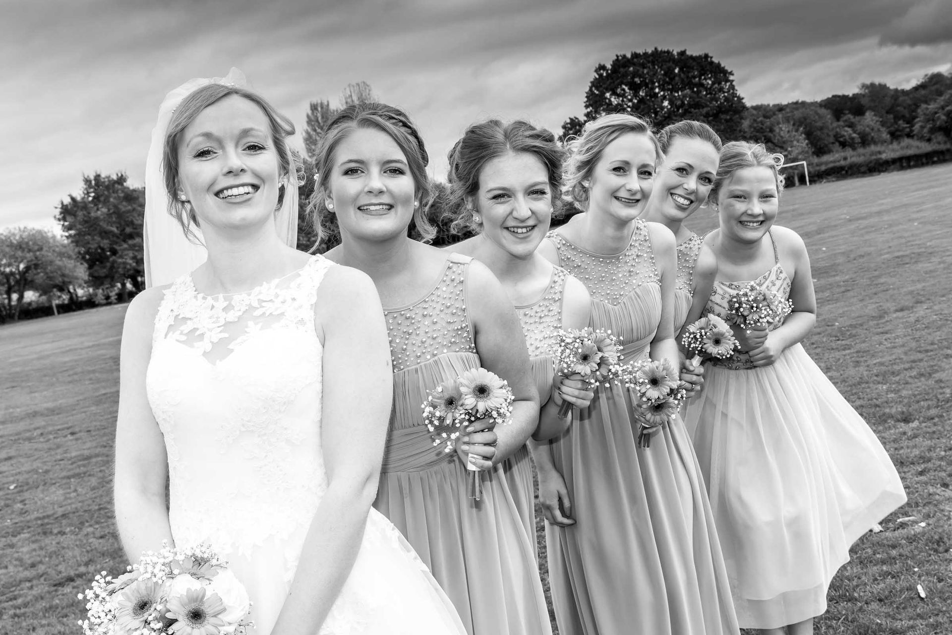 A bride and her bridesmaids are posing for a black and white photo.