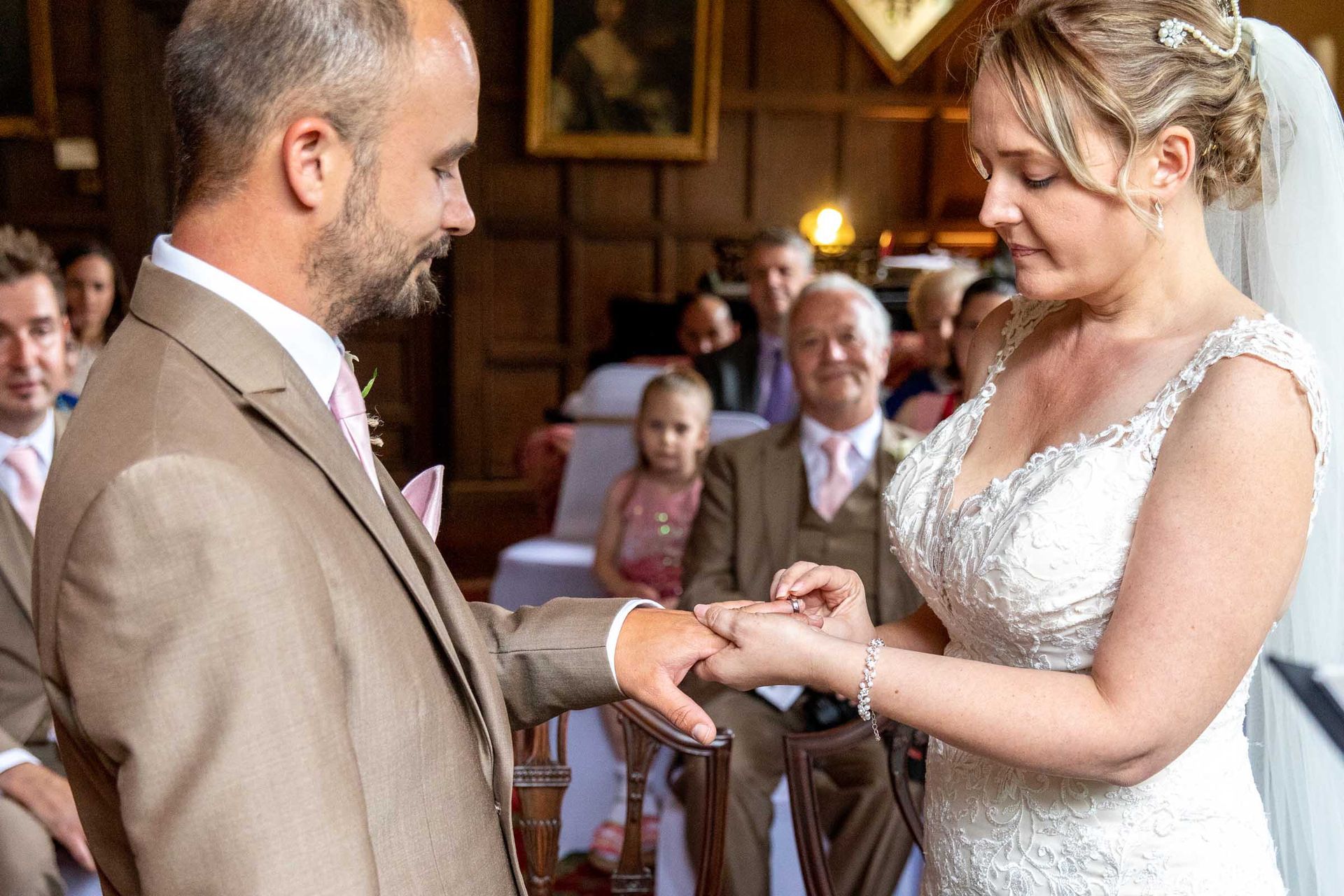 A bride is putting a wedding ring on the groom 's finger.