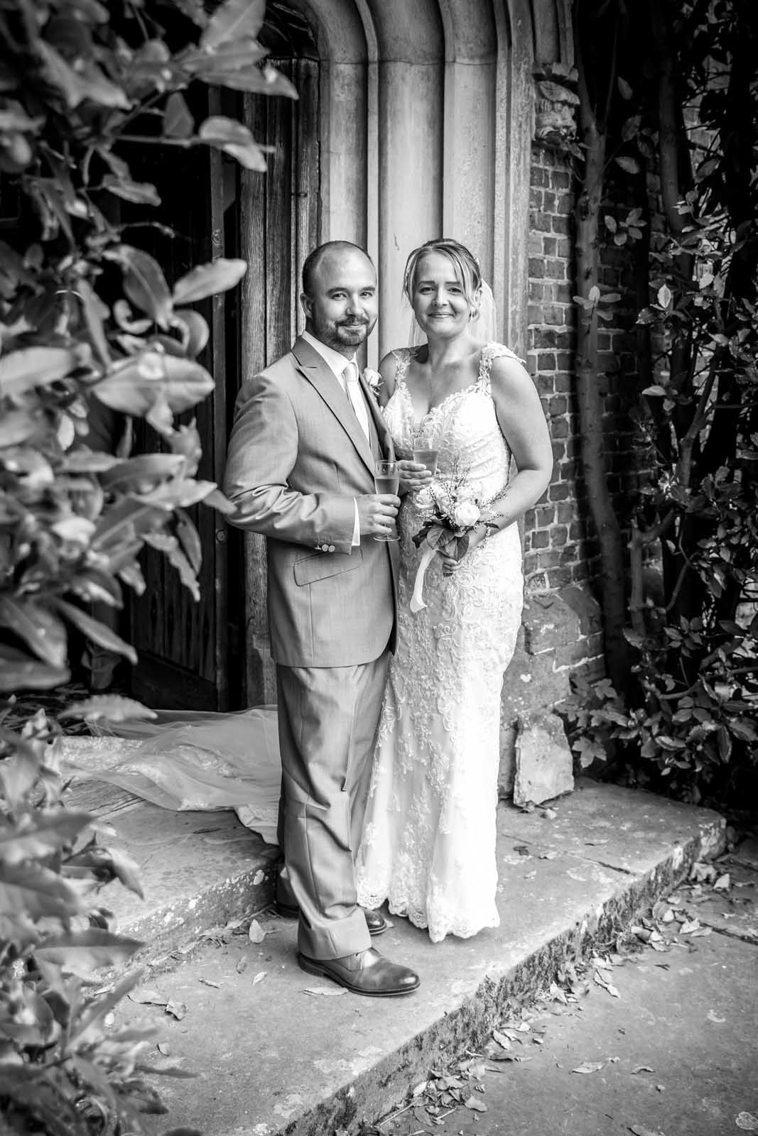 A bride and groom are posing for a black and white photo in front of a building.