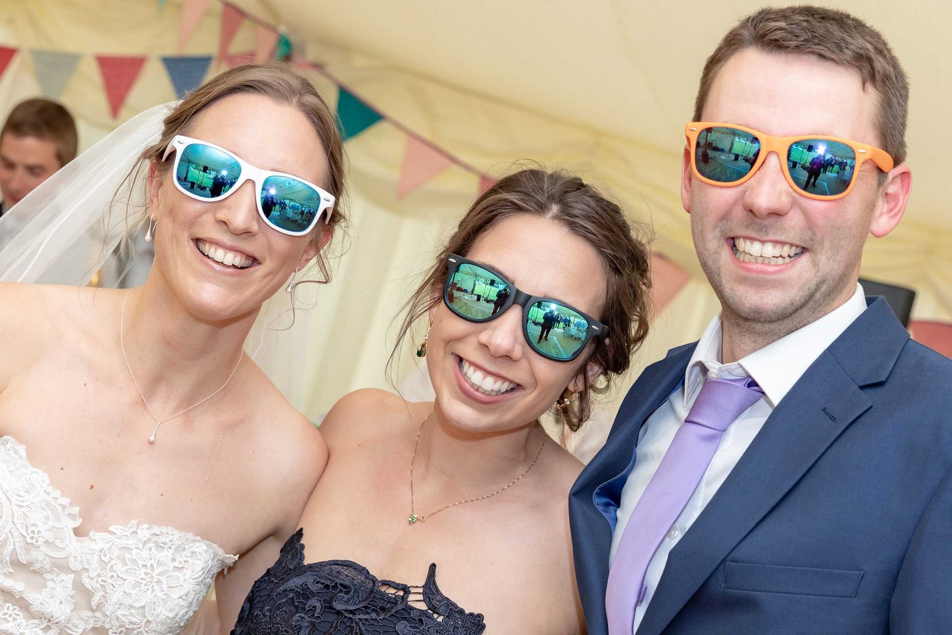 A bride and groom are posing for a picture with two women wearing sunglasses.